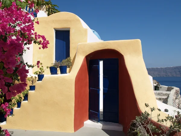 Блакитні двері на сонячно жовтому будинку з видом на море — стокове фото