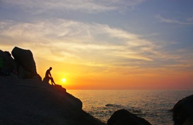 Silhouette of a man on the cliff clipart