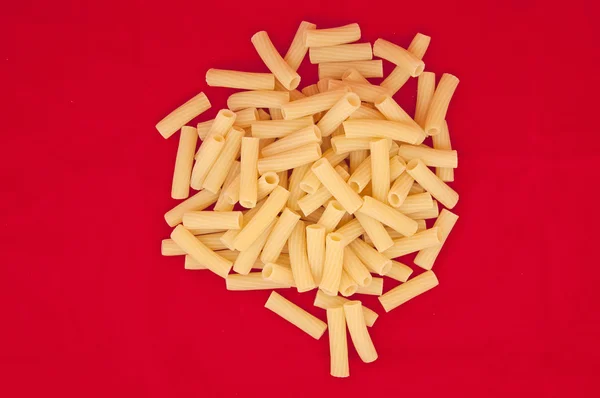 Heap of italian pasta on red background