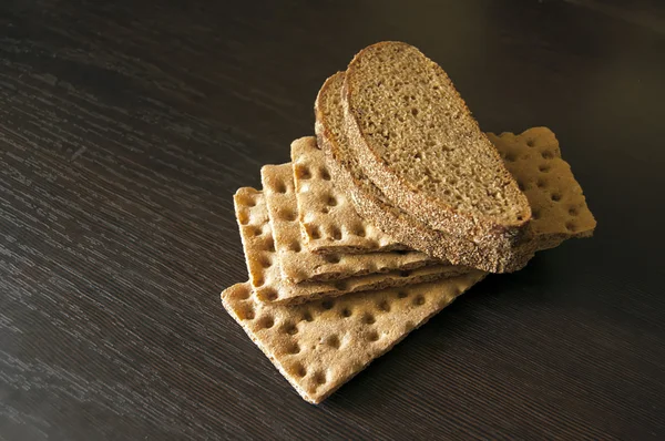 Коричневый хлеб и хрустящий на деревянном фоне — стоковое фото