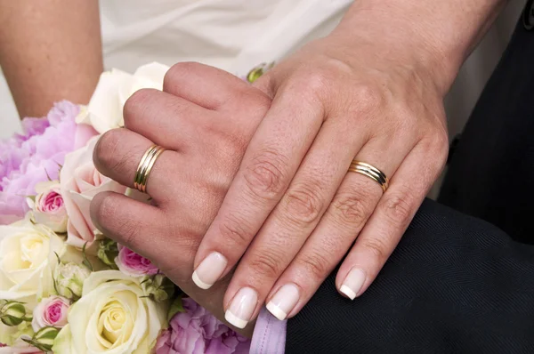 Snubní prsteny, ruce a kyticí růží. — Stock fotografie