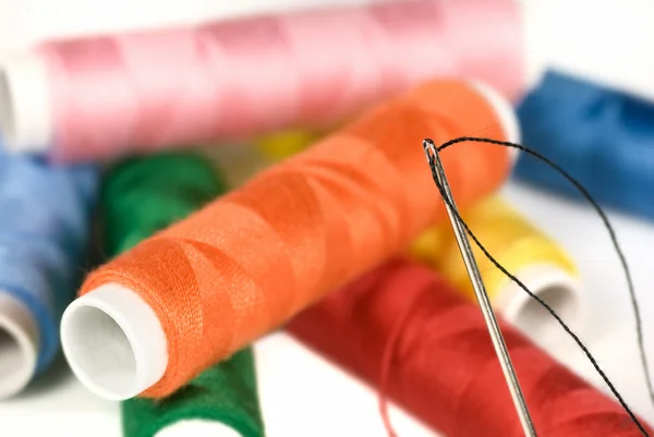 Multi colored cotton with threaded needle — Stock Photo, Image