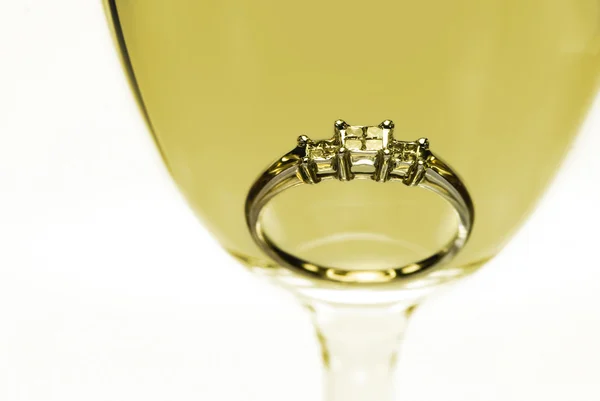 Diamond ring i ett glas vitt vin — Stockfoto