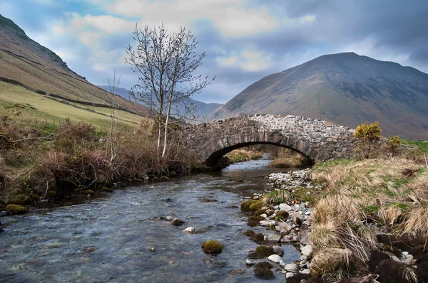 Mountain Stream flowing under a stone bridge — Stock Photo, Image