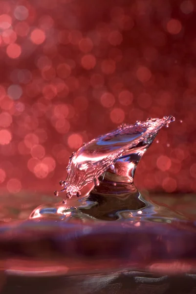 Water drop collision against a red background — Stock Photo, Image