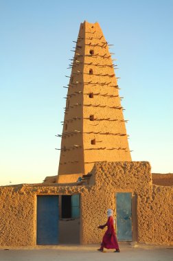 A man walking in front of the Agadez mosque clipart