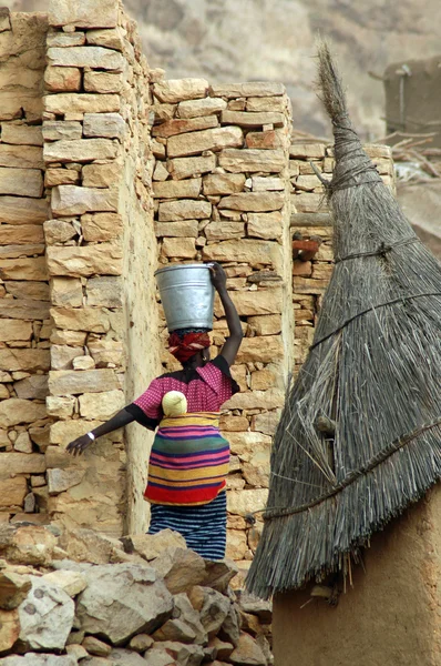 Dogon Frau trägt Eimer und Kind in mali — Stockfoto