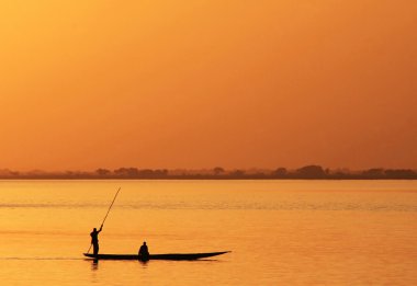 Silhouette of African fisherman in canoe clipart
