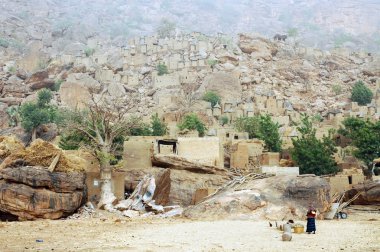 A Dogon woman in front of her village clipart