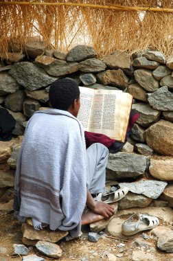 Young priest reading from bible clipart