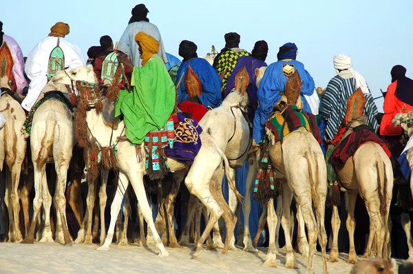 Homem cavalgando atrás de um grupo de Tuareg em camelos — Fotografia de Stock