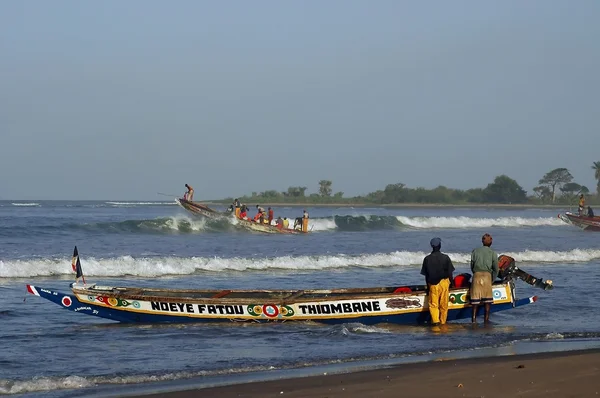 Afrikanische Fischer starten mit ihrem Boot ins Meer lizenzfreie Stockbilder
