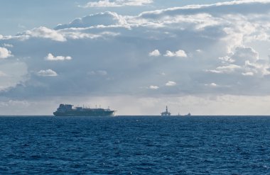 LNG carrier passing an oil field in southern Mediterranean clipart