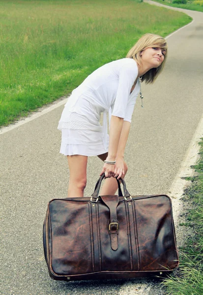 Chica tirando de una maleta de cuero — Foto de Stock
