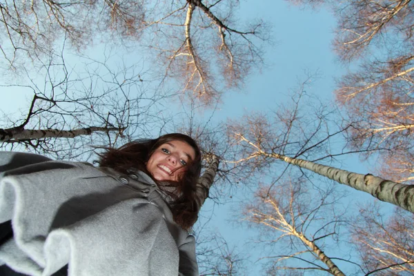 Chica joven contra los árboles y el cielo — Foto de Stock