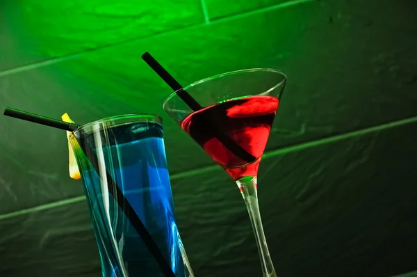 A red cocktail and a blue longdrink on a green background Stock Picture