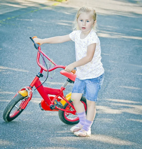 Kleines blondes Mädchen mit rotem Fahrrad — Stockfoto