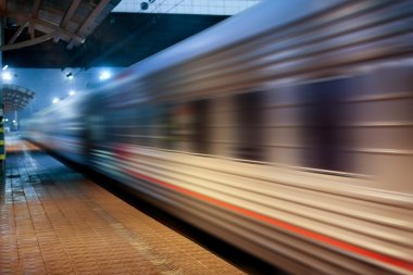 Train moving at station along platform clipart