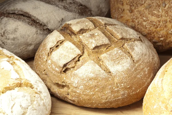 Asortyment pieczonego chleba na drewnianym stole — Zdjęcie stockowe
