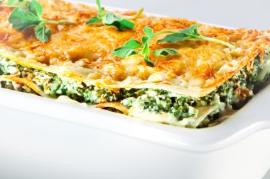 Italian cuisine. Spinach lasagna with basil. Macro clipart