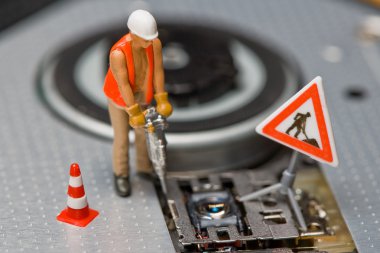 Miniature figures working on a DVD drive. clipart