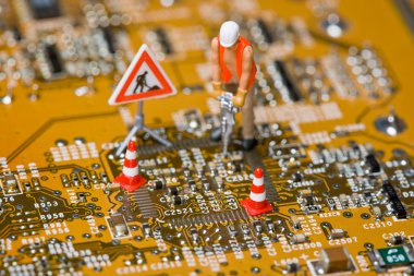 Miniature figures working on a circuit board. clipart