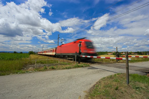 Pociąg przechodzącej przez Przejazd kolejowy. — Zdjęcie stockowe