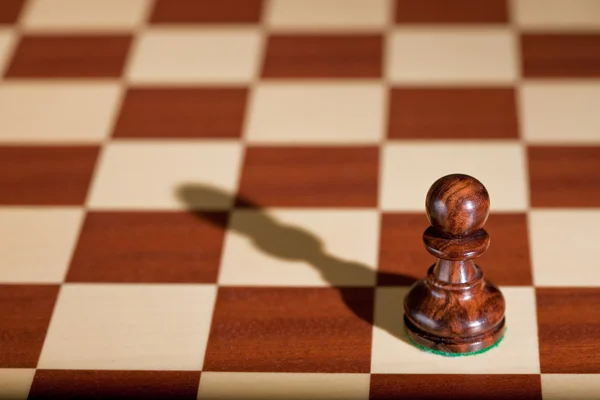 Шахматная фигура - черная пешка на шахматной доске . — стоковое фото