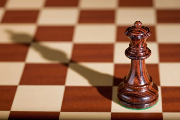 Šachová figurka - černá královna na šachovnici. — Stock fotografie