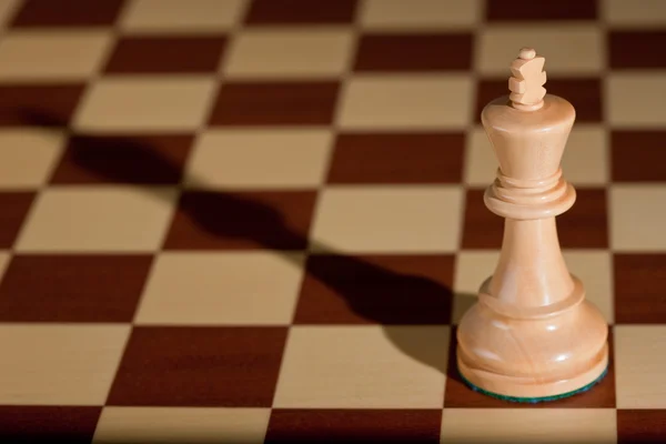 Pieza de ajedrez - un rey blanco en un tablero de ajedrez . — Foto de Stock
