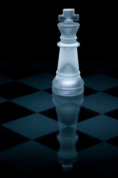 Peças de xadrez de vidro em um tabuleiro de xadrez de vidro com reflexão,  sobre um fundo preto.