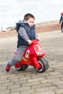 Boy riding his toy bike clipart