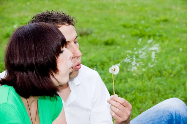 Ungt par i en park med en blåsa blomma — Stockfoto