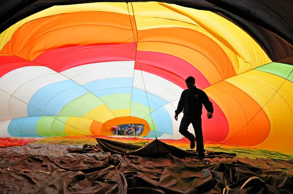 Homem dentro de um balão de ar quente colorido inflando — Fotografia de Stock