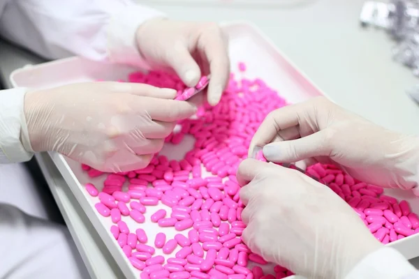 Händer som håller piller - kvalitetskontroll — Stockfoto