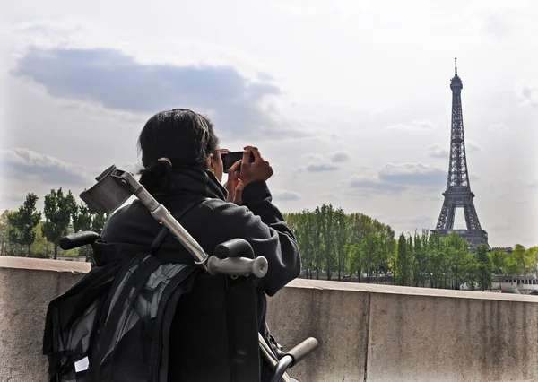 Femme en fauteuil roulant prenant une photo de la tour Eiffel — Photo