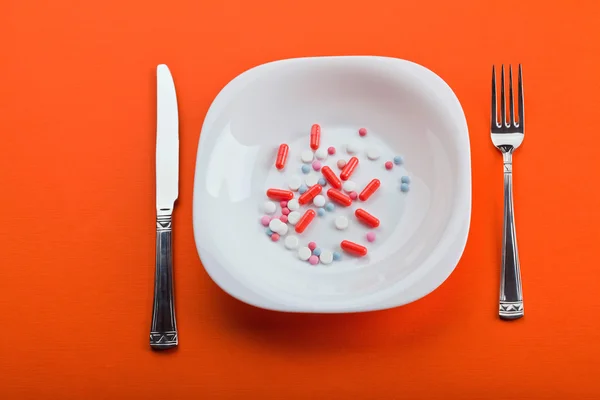 Pillole su piatto con forchetta e coltello — Foto Stock