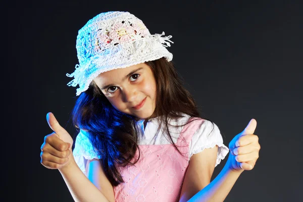 Little girl with a hat making OK sign, black background — Stock Photo, Image