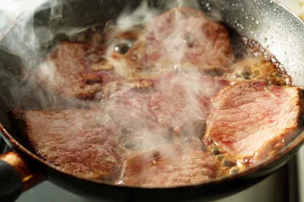 Τηγάνισμα το κρέας σε ένα τηγάνι με ατμών — Φωτογραφία Αρχείου