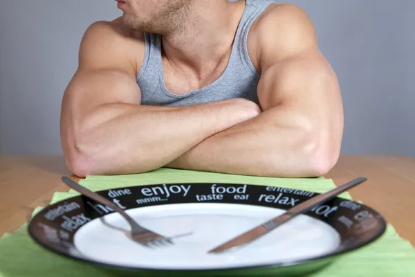 Muskulöser Mann mit leerem Teller — Stockfoto