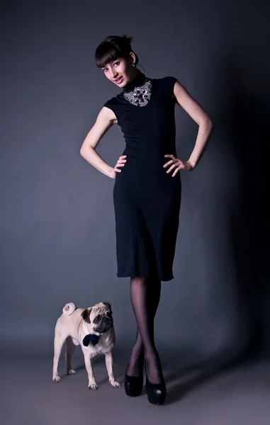 Elegant young woman with a pug dog in studio