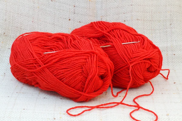 Deux boules rouges (pinces) de fil et crochet à tricoter — Photo