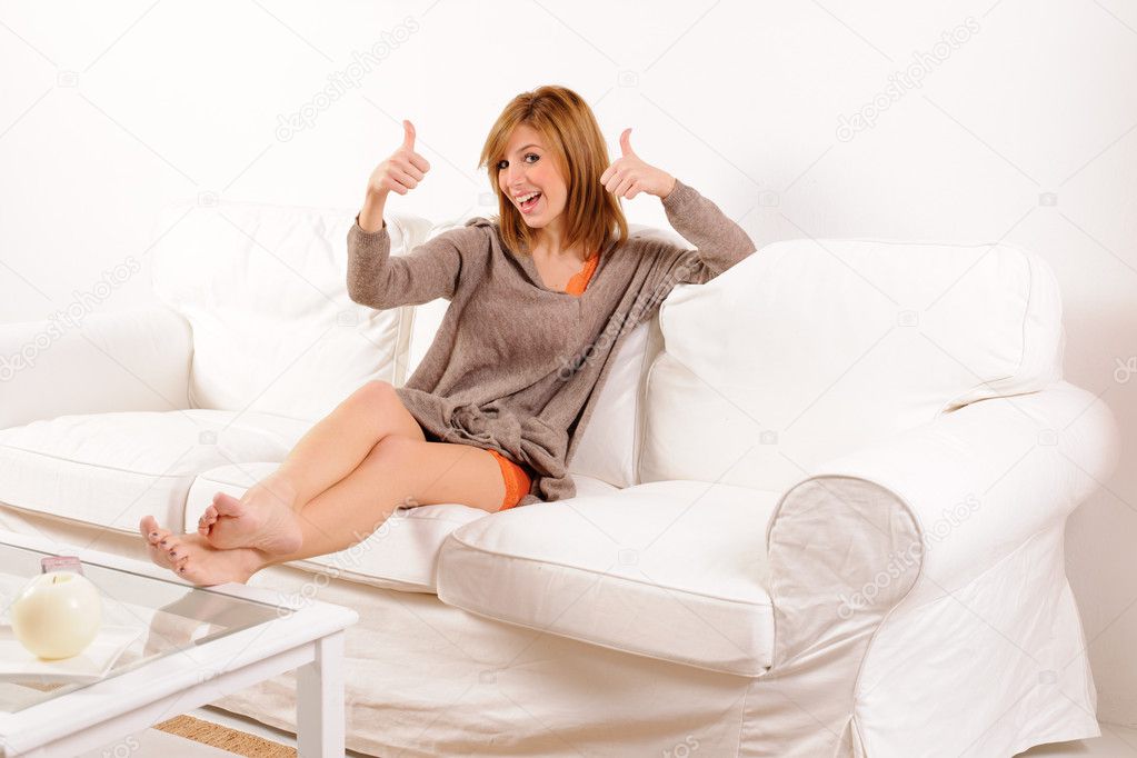 Young woman thumbs up on the sofa
