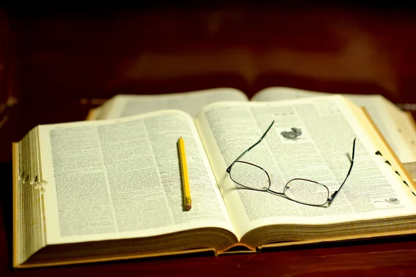 Öppna bok med penna och glasögon — Stockfoto