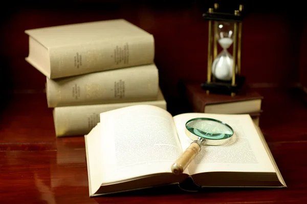 Böcker med förstoringsglas och timglas — Stockfoto