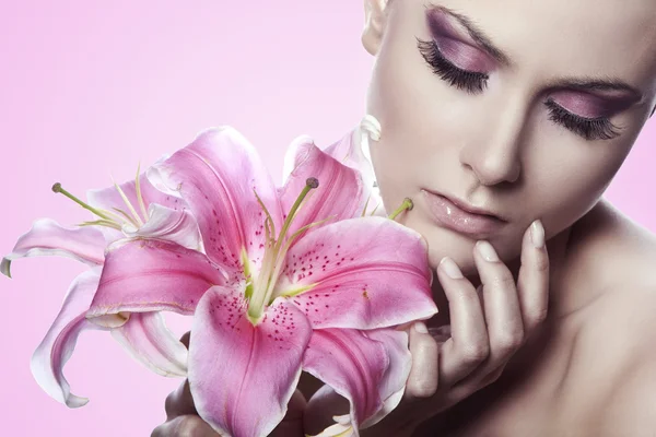 Vacker frisk kvinna med liljor på rosa bakgrund — Stockfoto