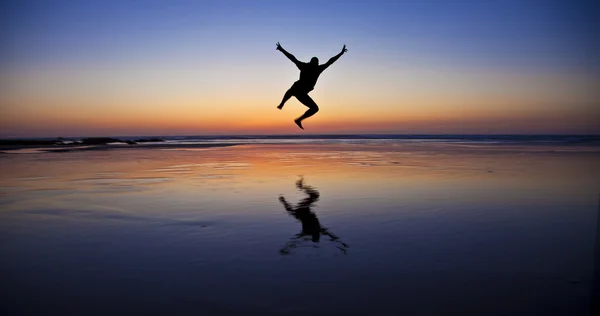 Silhouette eines springenden Mannes am Strand am Meer — Stockfoto