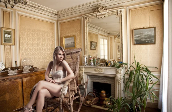 Όμορφη ξανθιά κοπέλα που σε μια λικνίζοντας καρέκλα, δίπλα στο τζάκι — Φωτογραφία Αρχείου