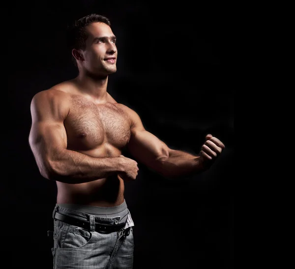 Muskulös man poserar på en svart bakgrund — Stockfoto