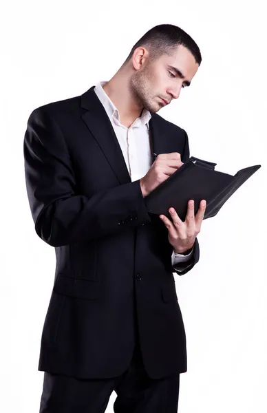 Elegante jovem empresário escrevendo em um caderno isolado em fundo branco — Fotografia de Stock
